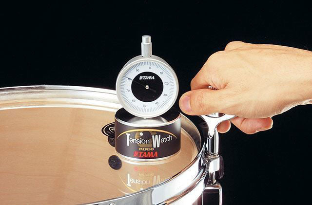 Tama TW100 Tension Watch for drums, GMI model, showing a close-up of the tension adjustment tool with brand logo visible.