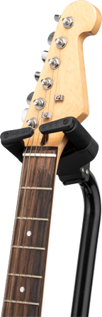 Hercules GS414BSW guitar stand holding an electric guitar, black metal frame with padded support arms for secure placement.