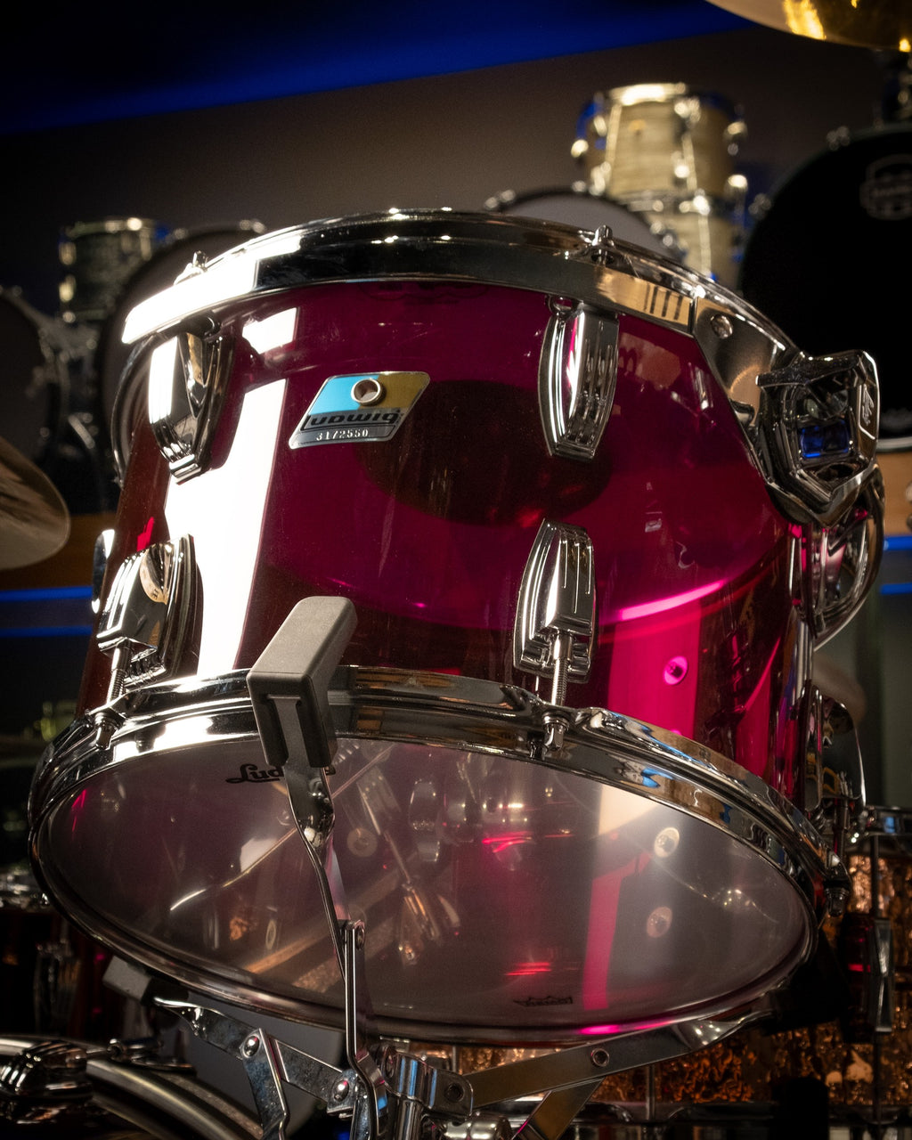 Ludwig Vistalite purple 3-piece drum kit with bass drum, snare, and tom drums, set up on a stage with cymbals.
