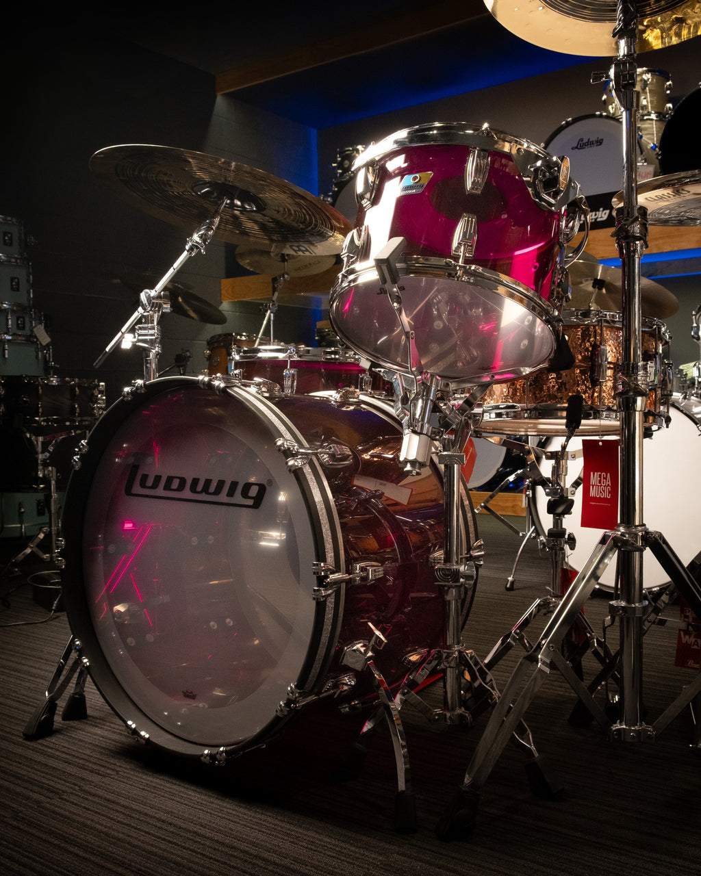 Ludwig Vistalite 3-piece purple drum kit with bass drum, snare, and tom drums, set up on a stage with drumsticks.