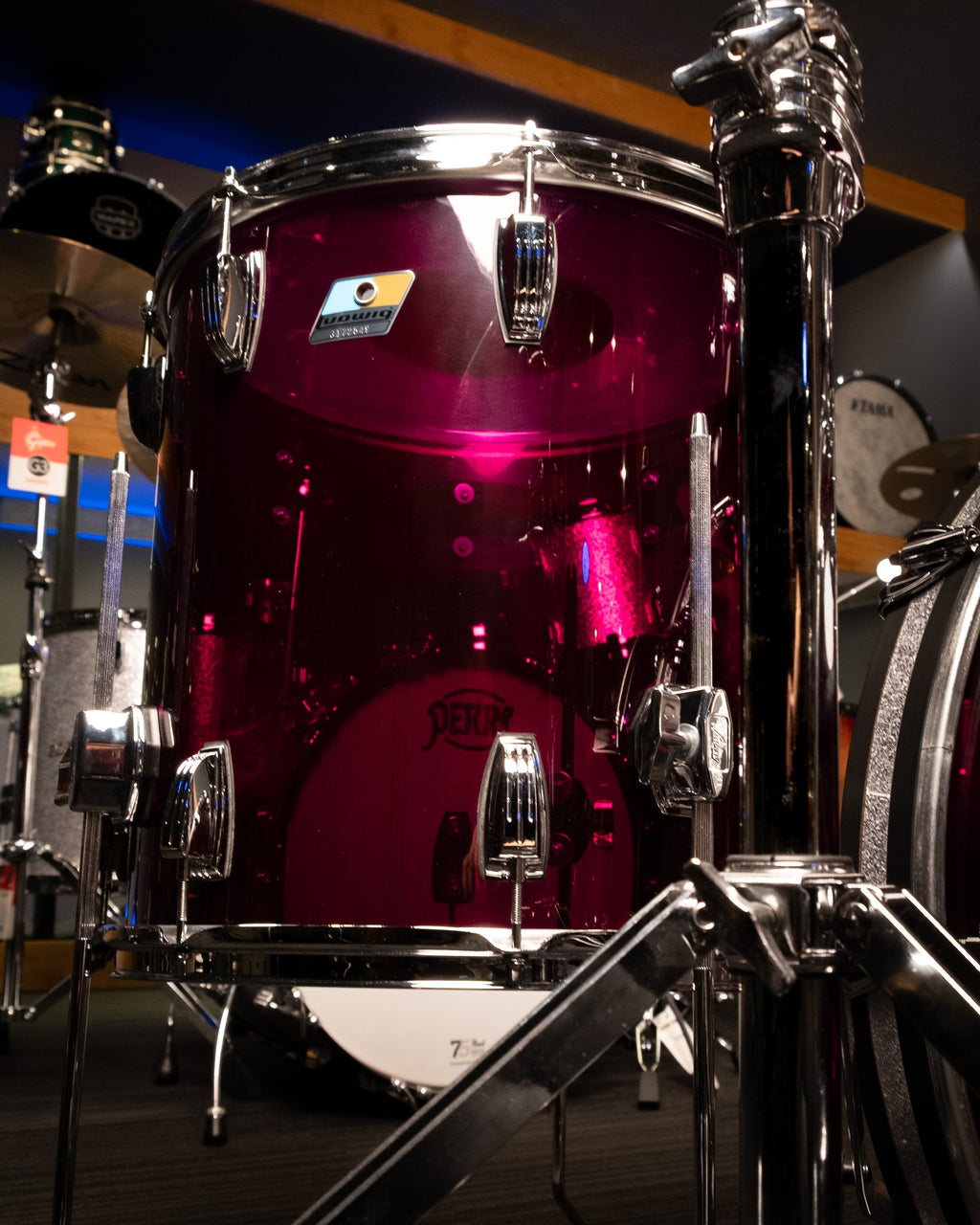 Ludwig Vistalite 3-piece purple drum kit with bass drum, toms, and snare drums, set up on a stage.