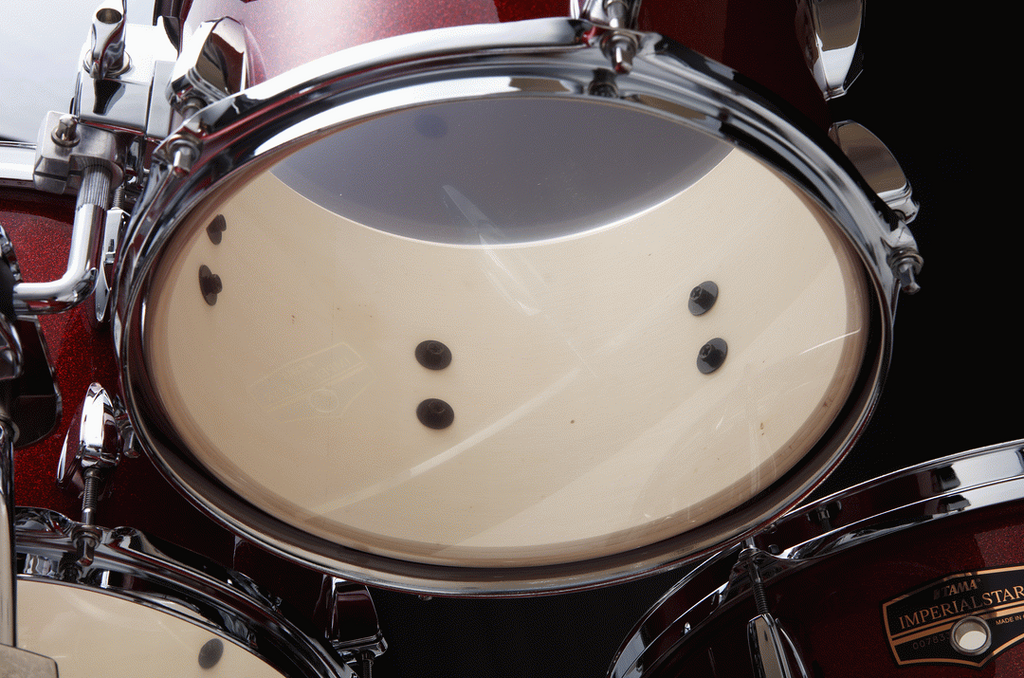 Tama Imperialstar 6-piece drum kit in Burnt Red Mist with bass, toms, snare, and cymbals on a stand, ready for performance.