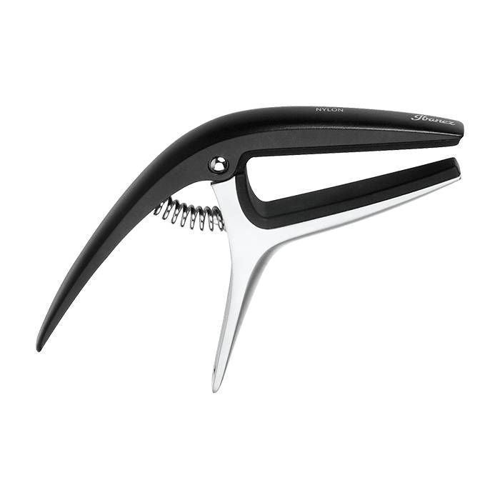Ibanez ICGC10 universal guitar capo clipped on the neck of an acoustic guitar, showing its black, compact design and adjustable tension.