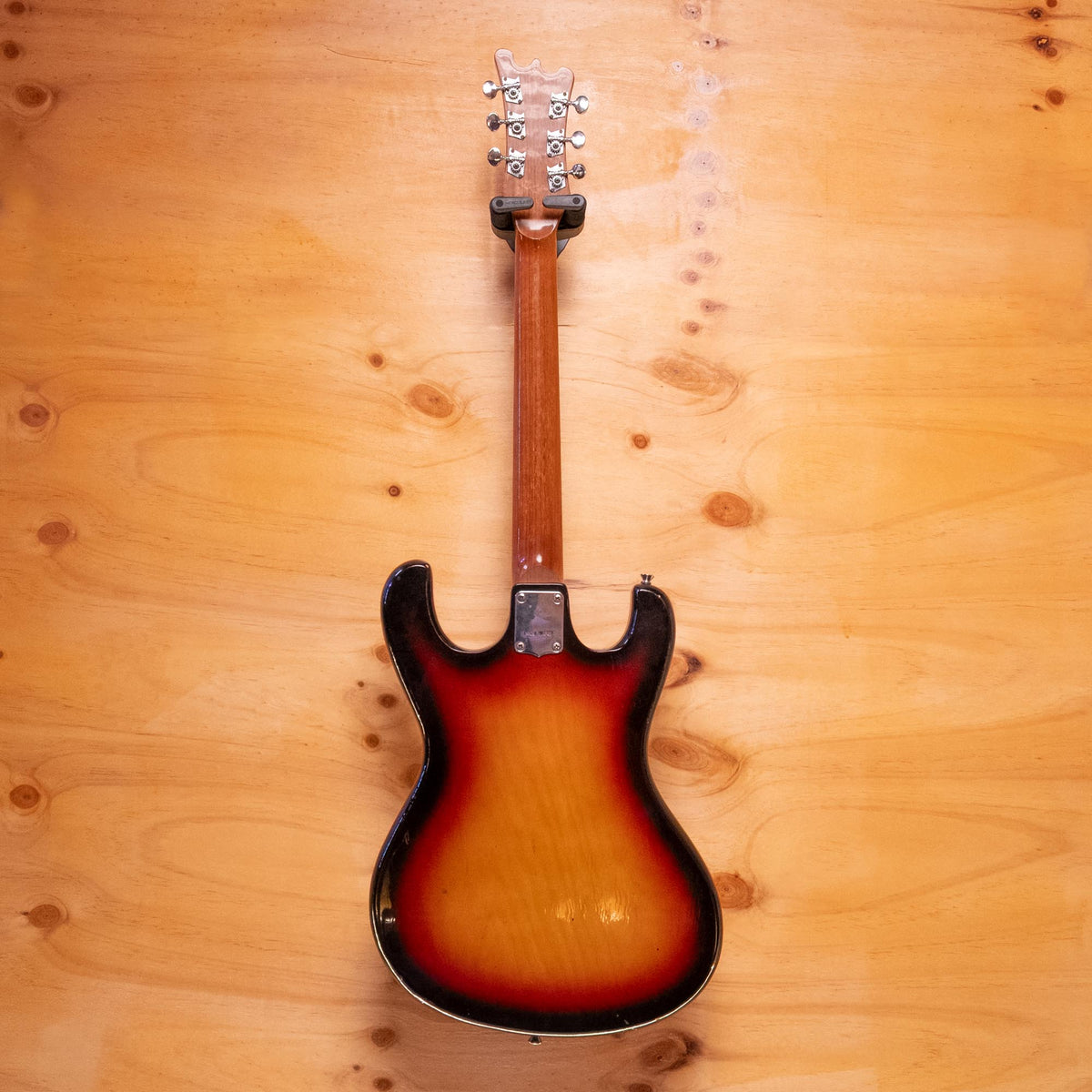 Preloved Guyatone electric guitar with a sleek body and six strings, shown on a stand with a sunlit background.