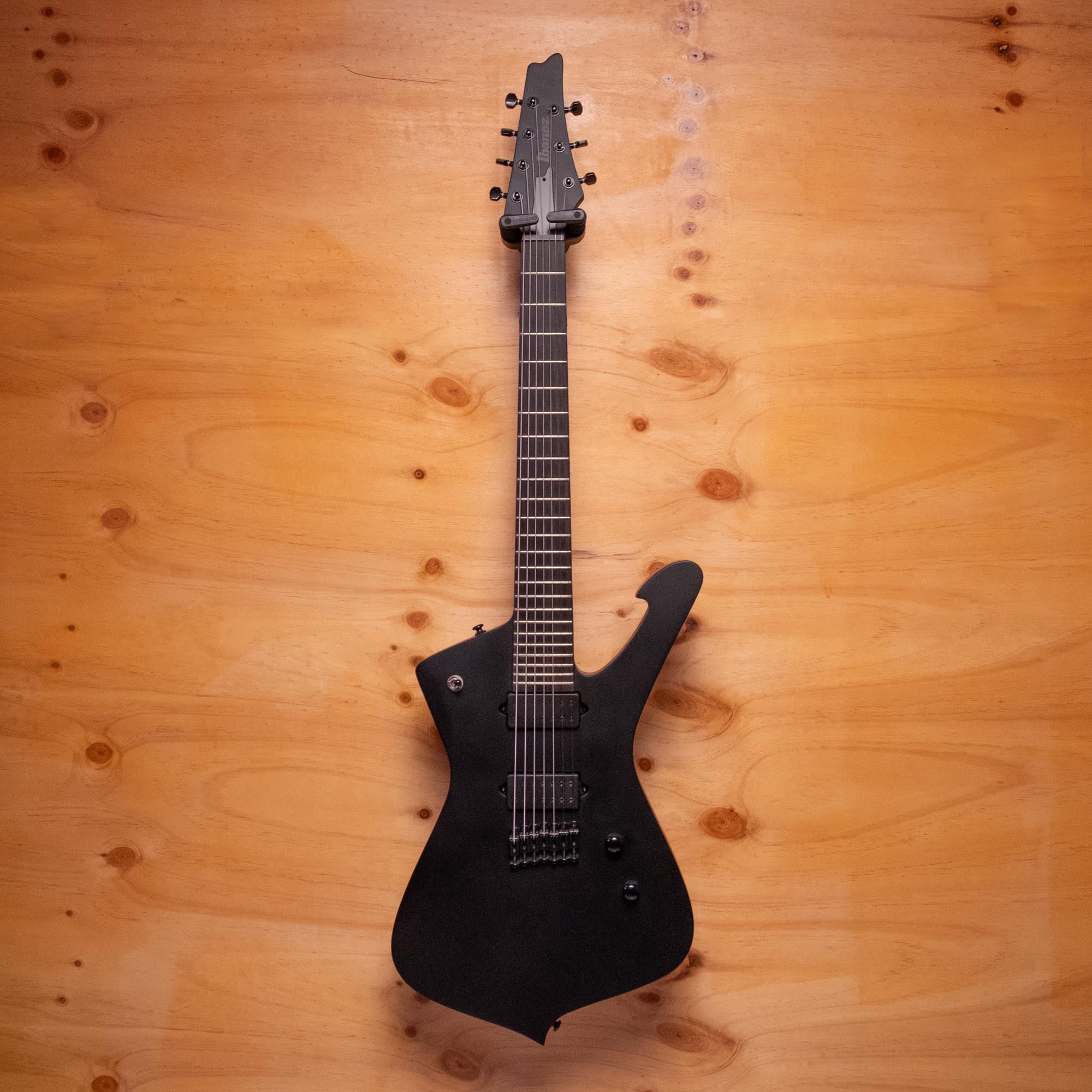 Ibanez ICTB721 Iceman Iron Label 7-string electric guitar in black flat, showing the distinctive body shape and six-string neck.