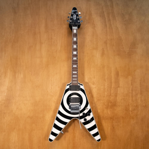 Preowned Gibson Copy Bullseye Flying V electric guitar with bold design, black finish, and distinctive shape, displayed on a stand.