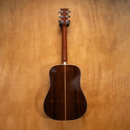 Martin D-28 dreadnought acoustic guitar with rich wood finish and six strings, shown from a side angle.