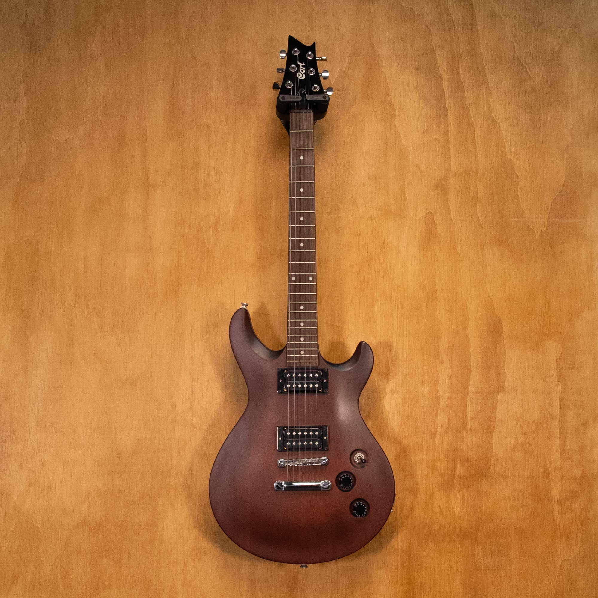 Preloved Cort M200 electric guitar with a sleek body, six strings, and pickups, displayed on a stand.