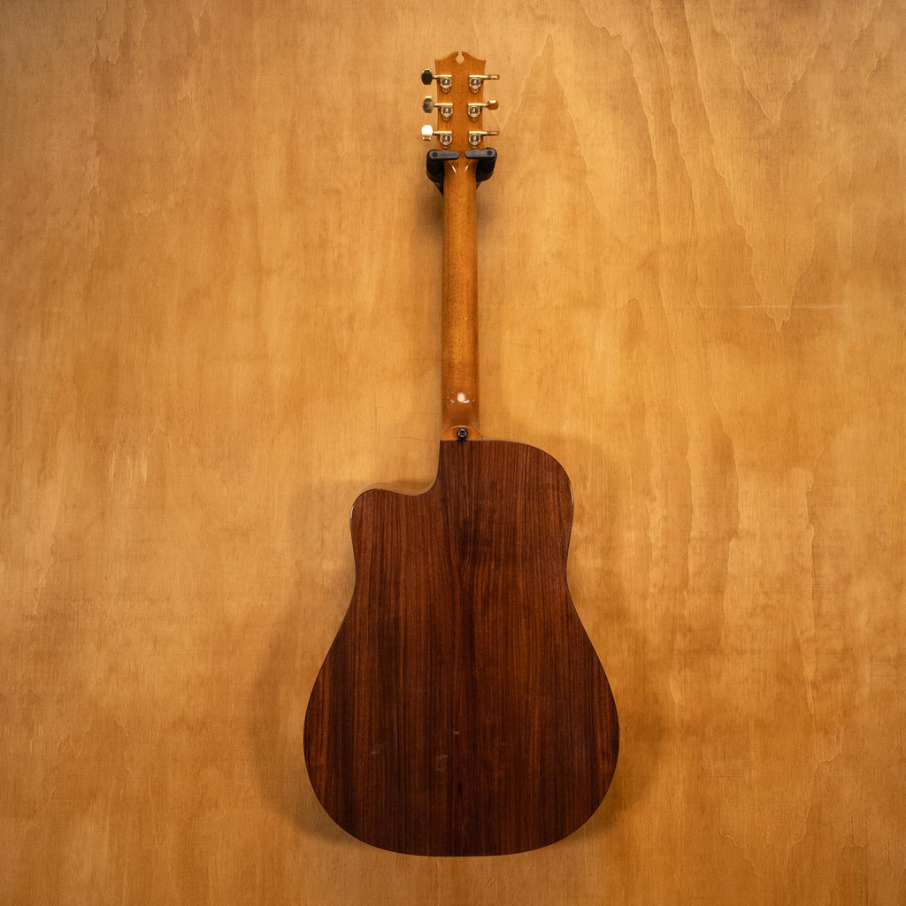 Maton Tommy Emmanuel TE1 acoustic guitar with natural wood finish, six strings, and detailed fretboard, shown from a front angle.