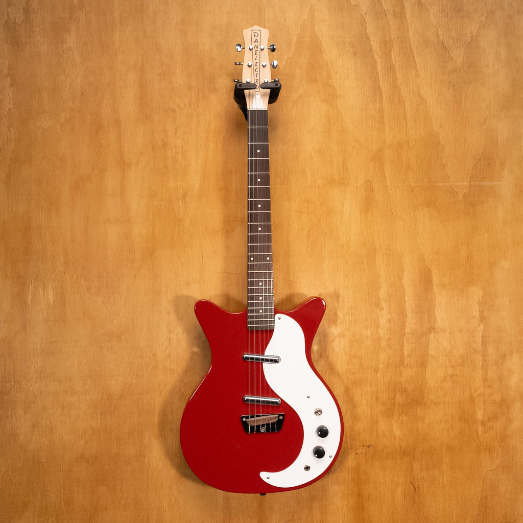 Red Danelectro Stock '59 electric guitar with double-cutaway body and vintage-style pickups, placed on a stand.