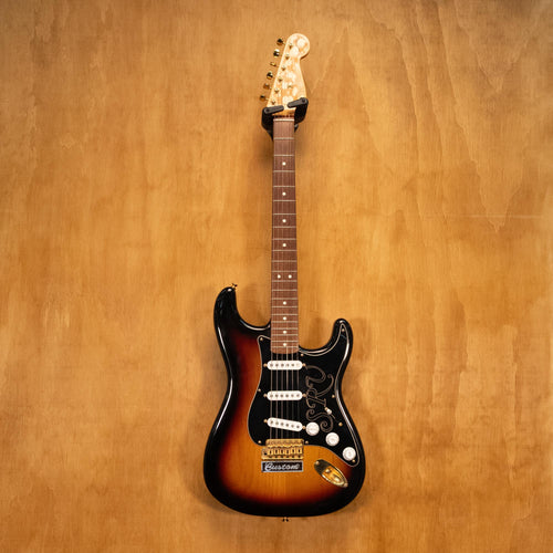 Fender SRV Stratocaster '04 electric guitar with sunburst finish, three pickups, and maple neck, resting on a guitar stand.