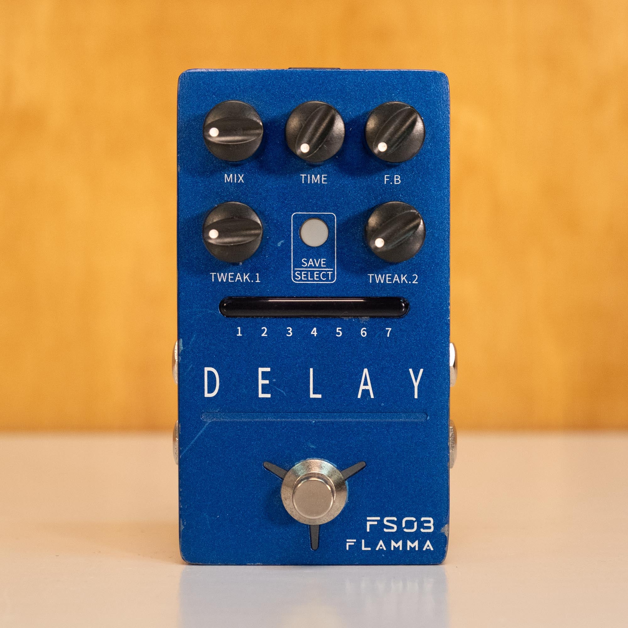 Flamma FS03 Delay guitar effects pedal, preowned, with knobs and input/output jacks visible on a wooden surface.