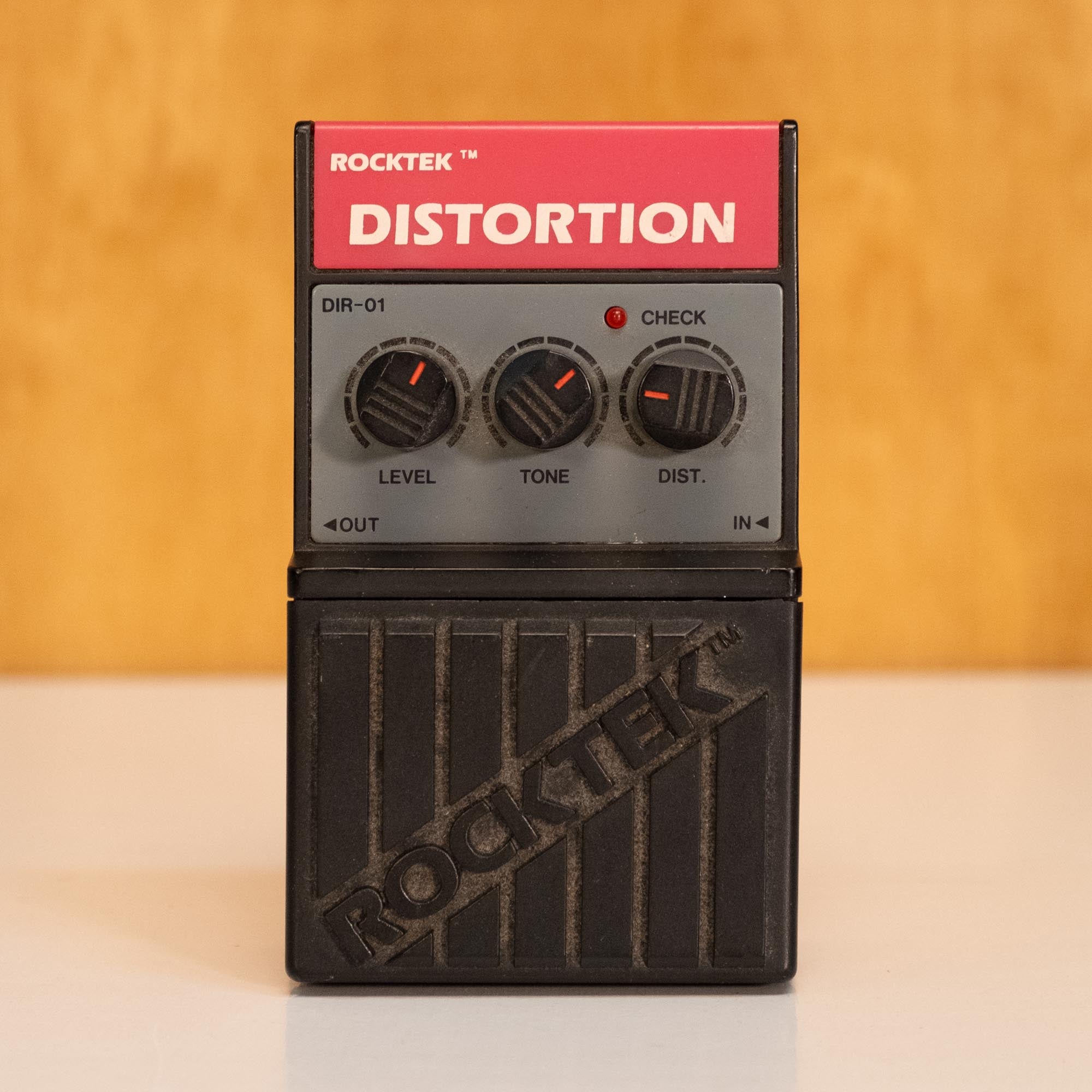 Rocktek DIR01 distortion guitar effects pedal with control knobs and input/output jacks on a white surface.