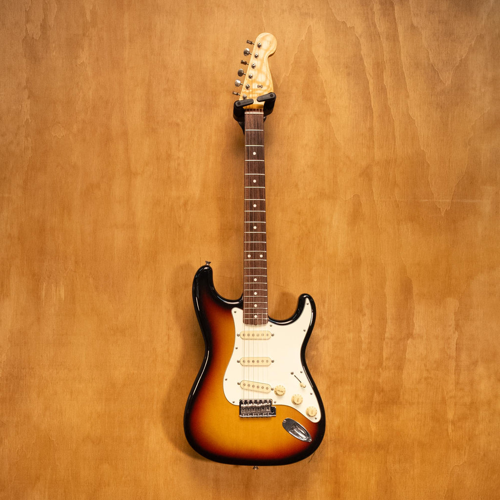 Fender Japan '62 Stratocaster electric guitar in 3-tone sunburst finish, with a vintage-style body and maple neck, displayed on a stand.