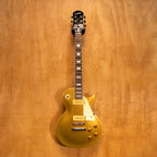 Epiphone 1956 Les Paul Standard Gold Top electric guitar with gold finish and vintage design, displayed on a stand.