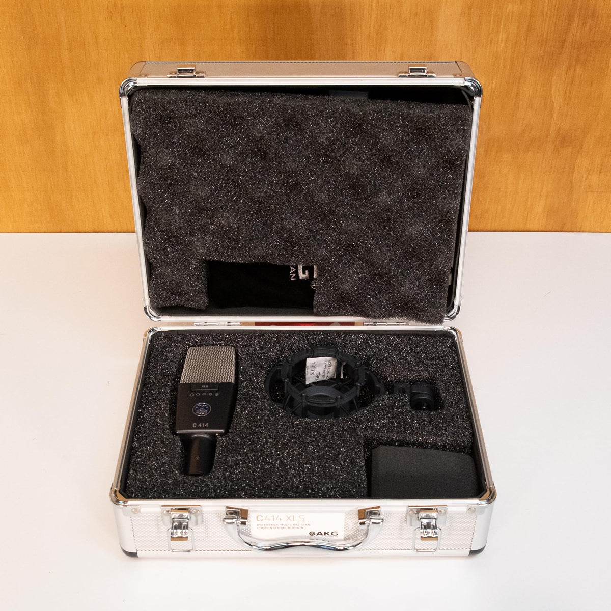 AKG C414 XLS condenser studio microphone shown in a black finish with multiple pickup patterns and professional audio equipment.