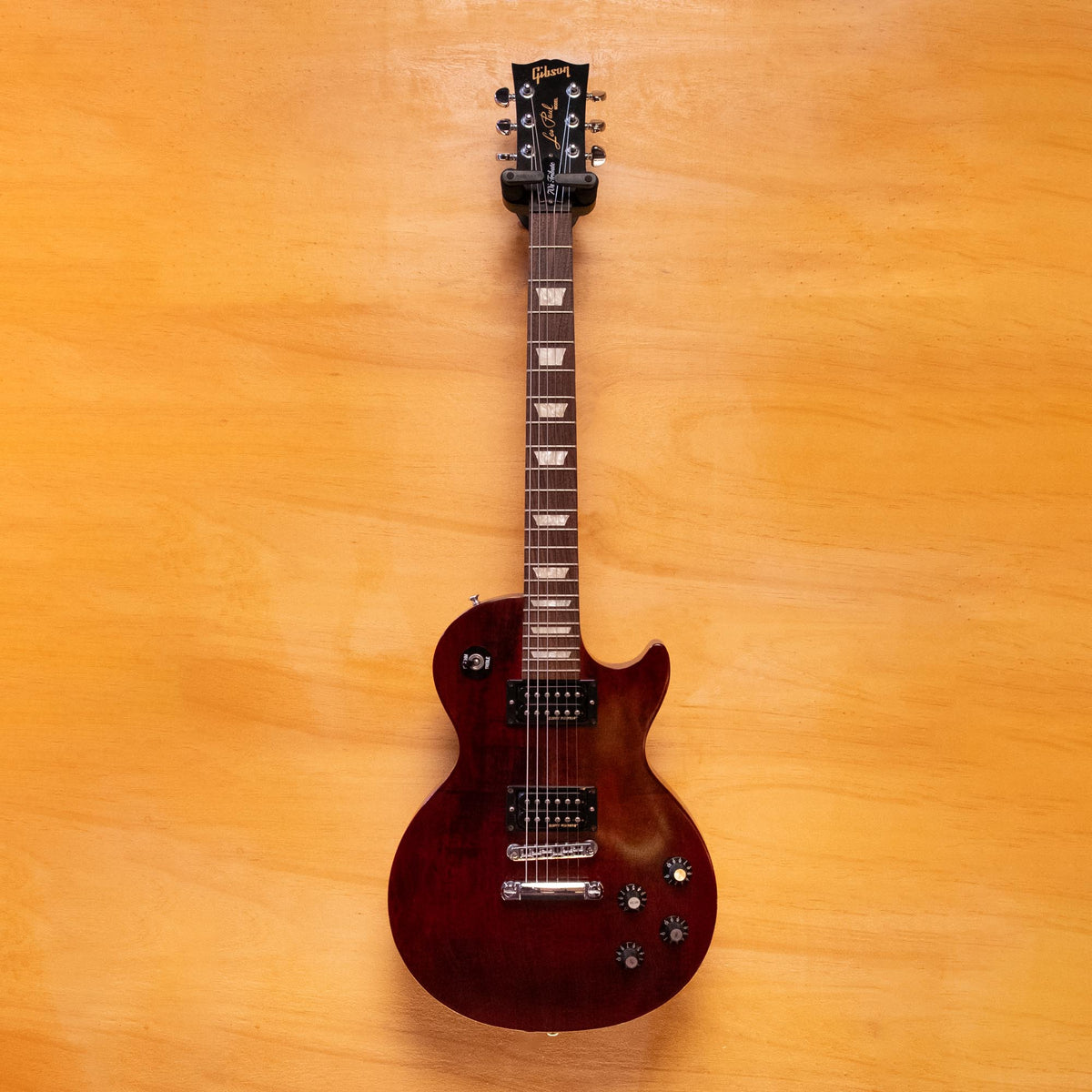 Gibson Les Paul '70s Tribute electric guitar with sunburst finish, double-cutaway body, and chrome hardware, shown on a stand.