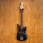 Fender JMJ Road Worn Mustang Bass Guitar in black with aged finish and vintage-style hardware, shown on a stand.