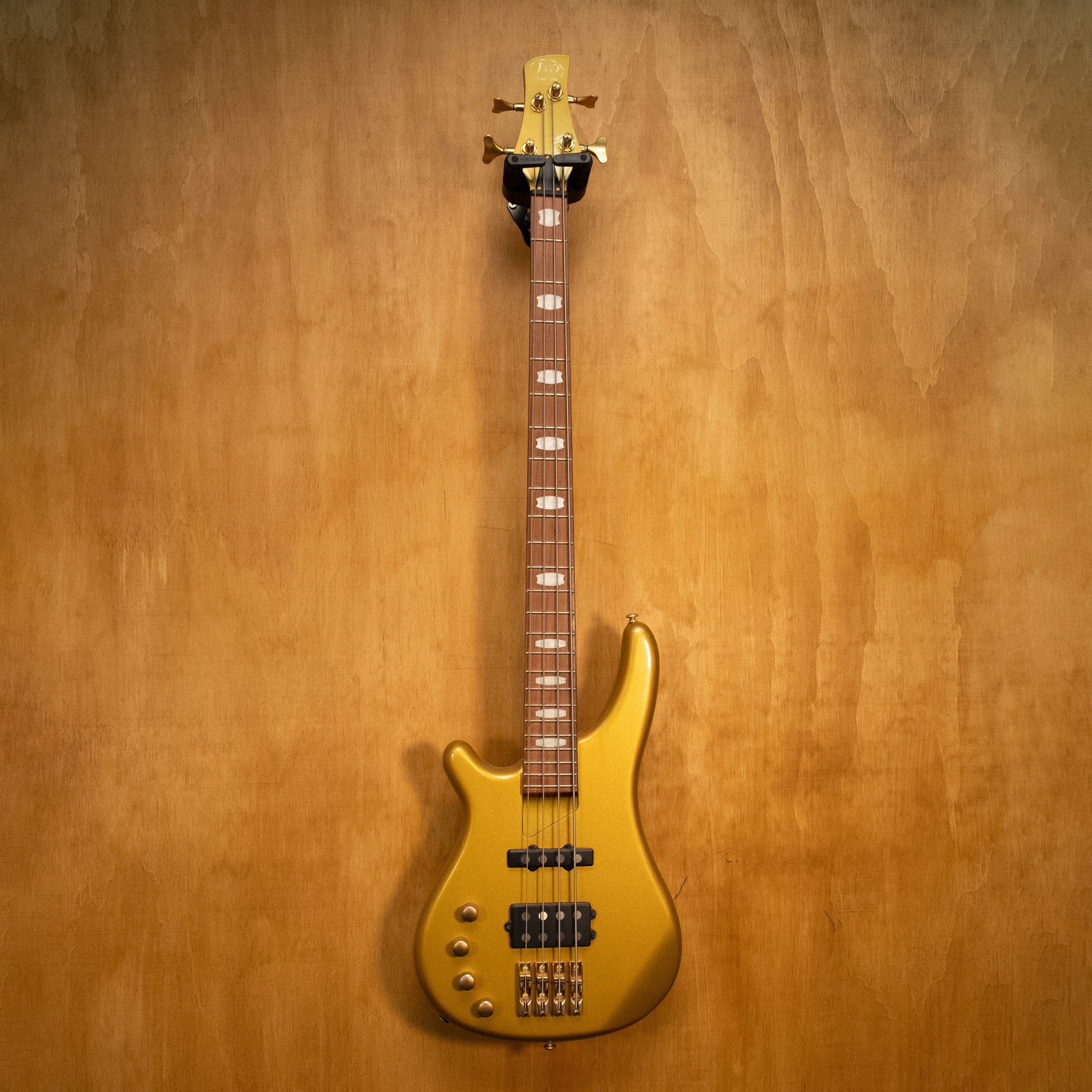 Left-handed J&D Luthiers active bass guitar in gold finish, showcasing the body shape and hardware details.