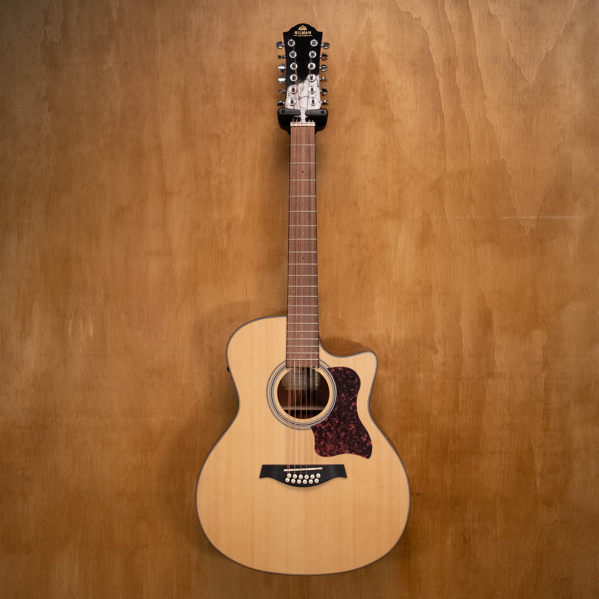 Gilman 12-string acoustic guitar with cutaway and pickup, showing the wooden body, neck, and strings in a natural light setting.