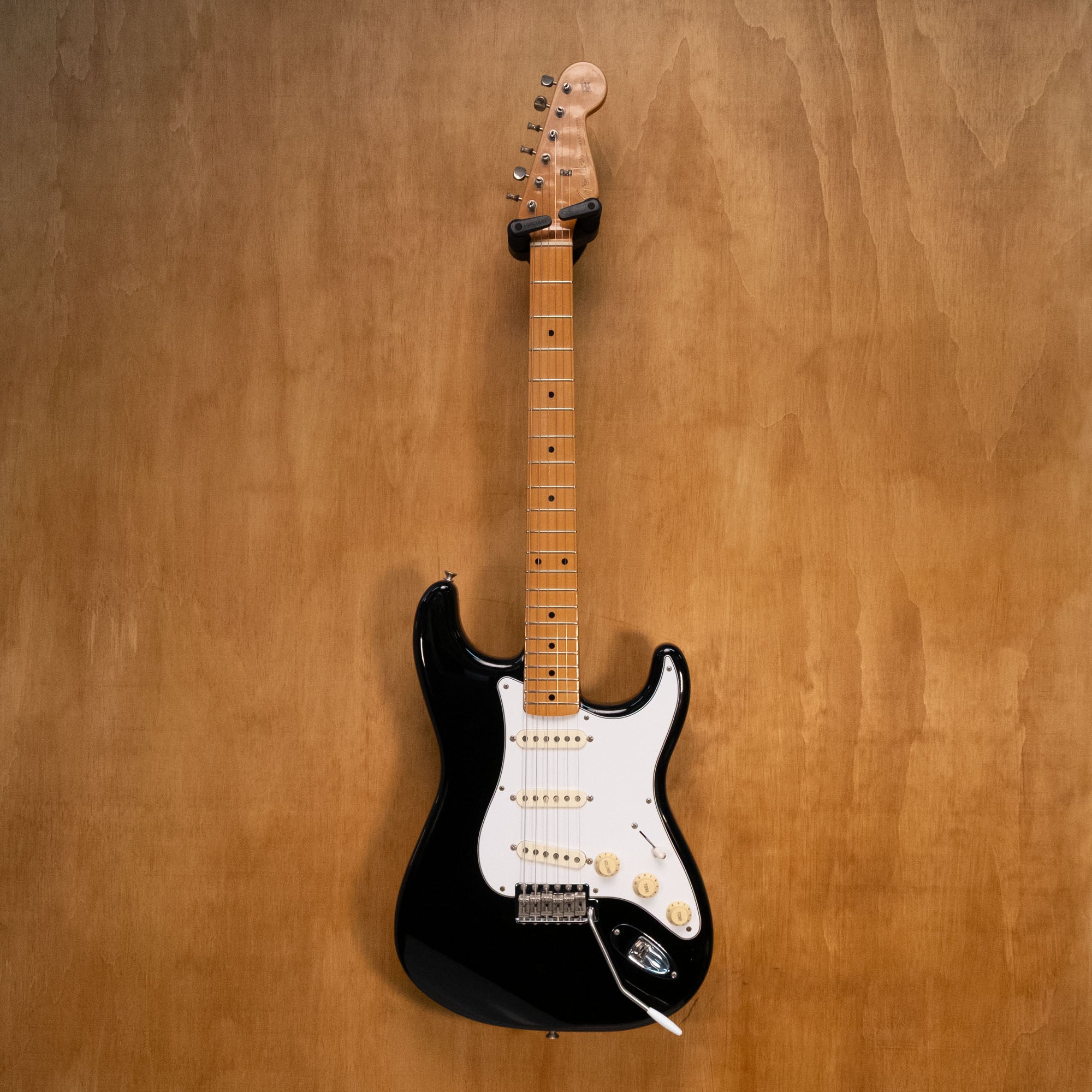Fender '50s Classic Stratocaster electric guitar in black with white pickguard and vintage-style tuning pegs, close-up view.