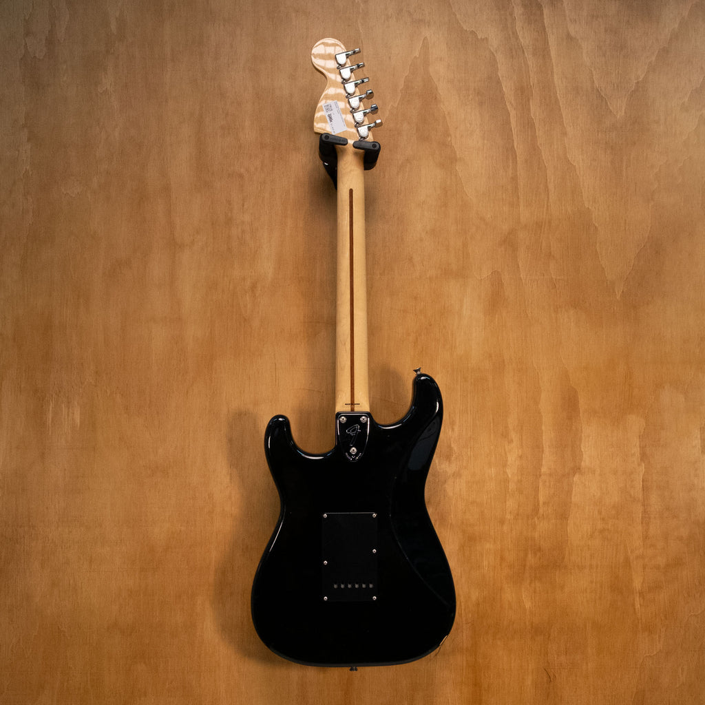Fender '72 Reissue Stratocaster electric guitar in black with maple neck, made in Japan, shown on a stand.