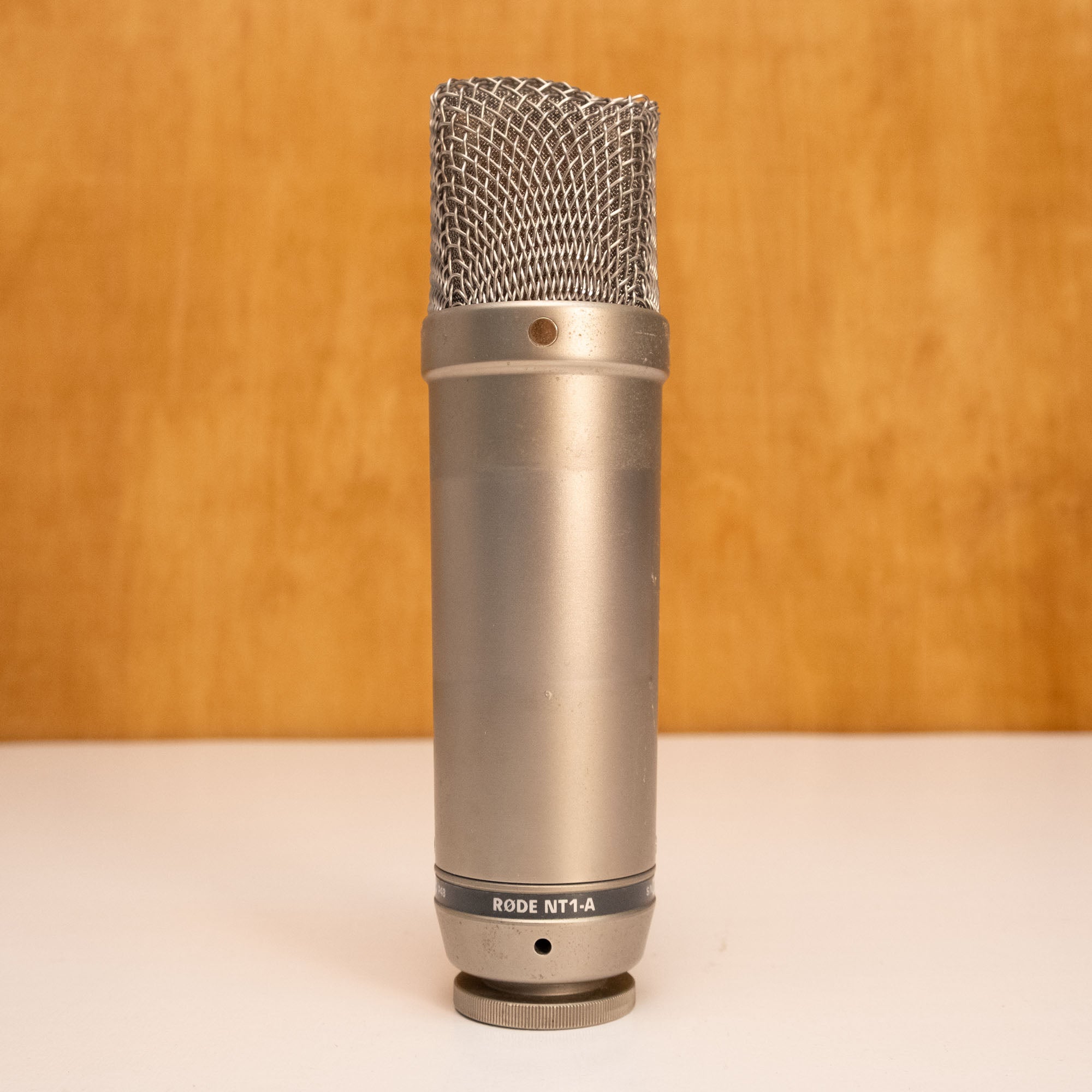 Rode NT1-A condenser studio microphone with shock mount and cable, close-up shot showing microphone detail and build quality.