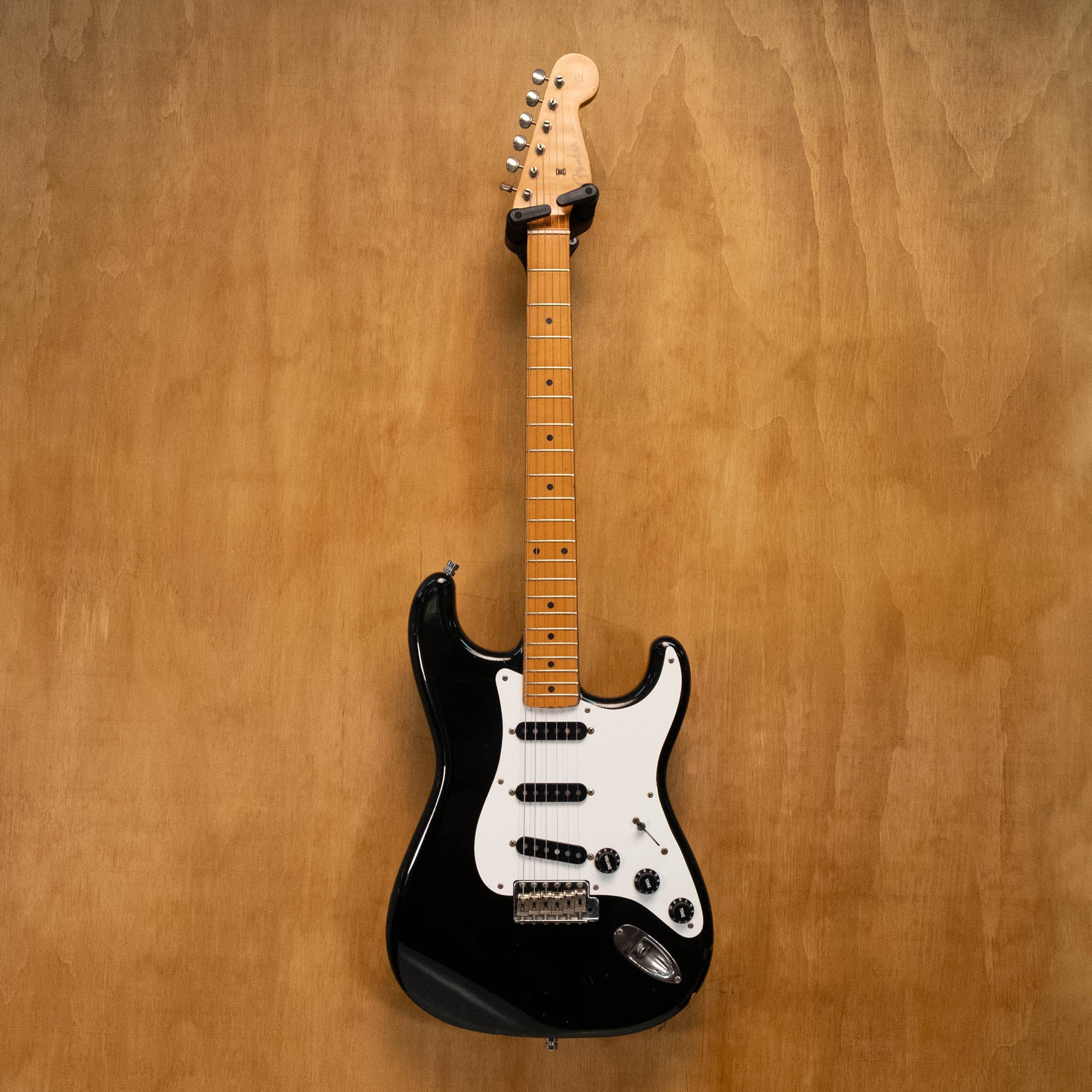 Fender '57 Stratocaster electric guitar in black, made in Japan, featuring a classic design and vintage styling, photographed on a white background.