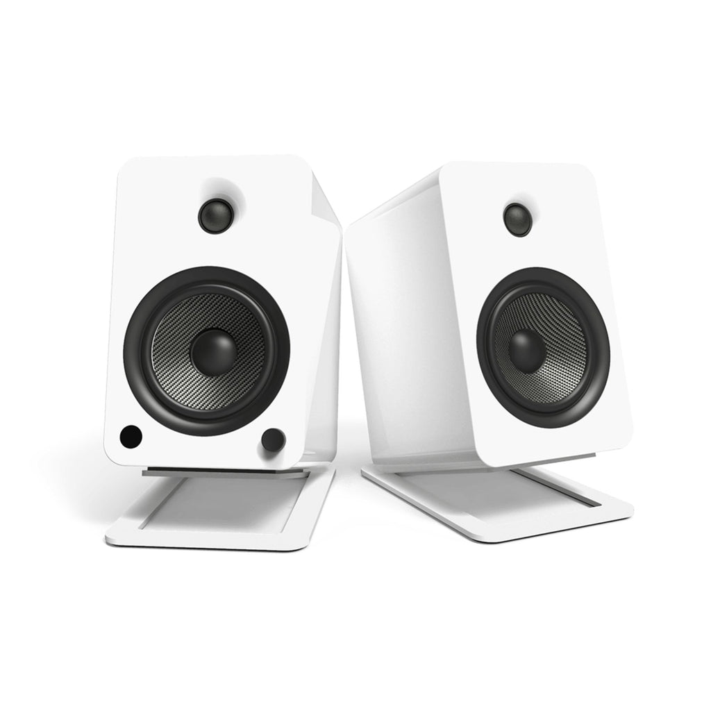 White Kanto KANS6W large desk top tilted speaker stands for studio monitors, shown on a workspace with speakers mounted.