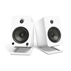White Kanto KANS6W large desk top tilted speaker stands for studio monitors, shown on a workspace with speakers mounted.