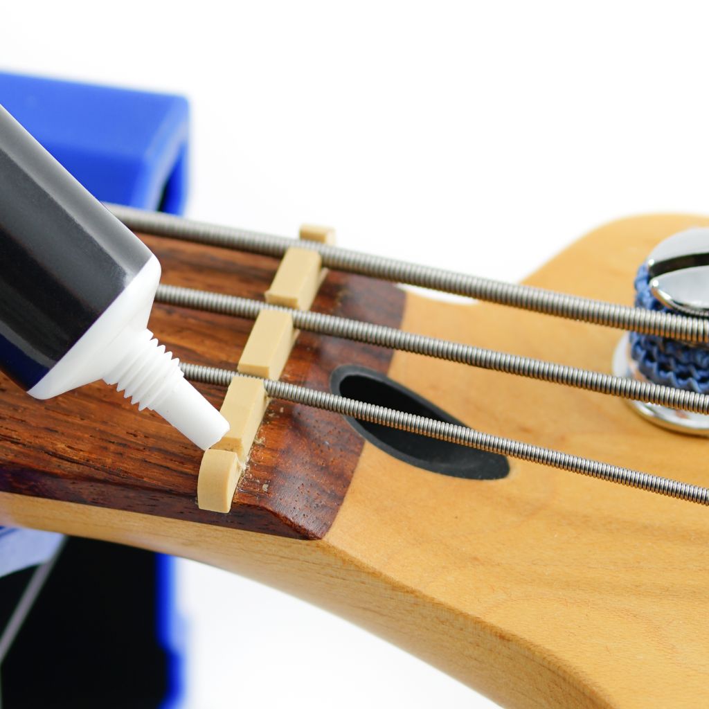 Music Nomad MN106 Tune It lubricant for guitar tuning pegs, in a small bottle with a black cap, used for guitar maintenance.