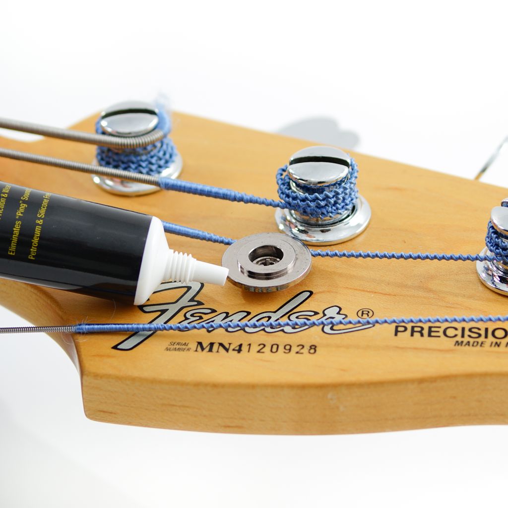 Music Nomad MN106 Tune It Lubricant for guitar tuning keys, in a small bottle with a black cap, designed for guitar maintenance.