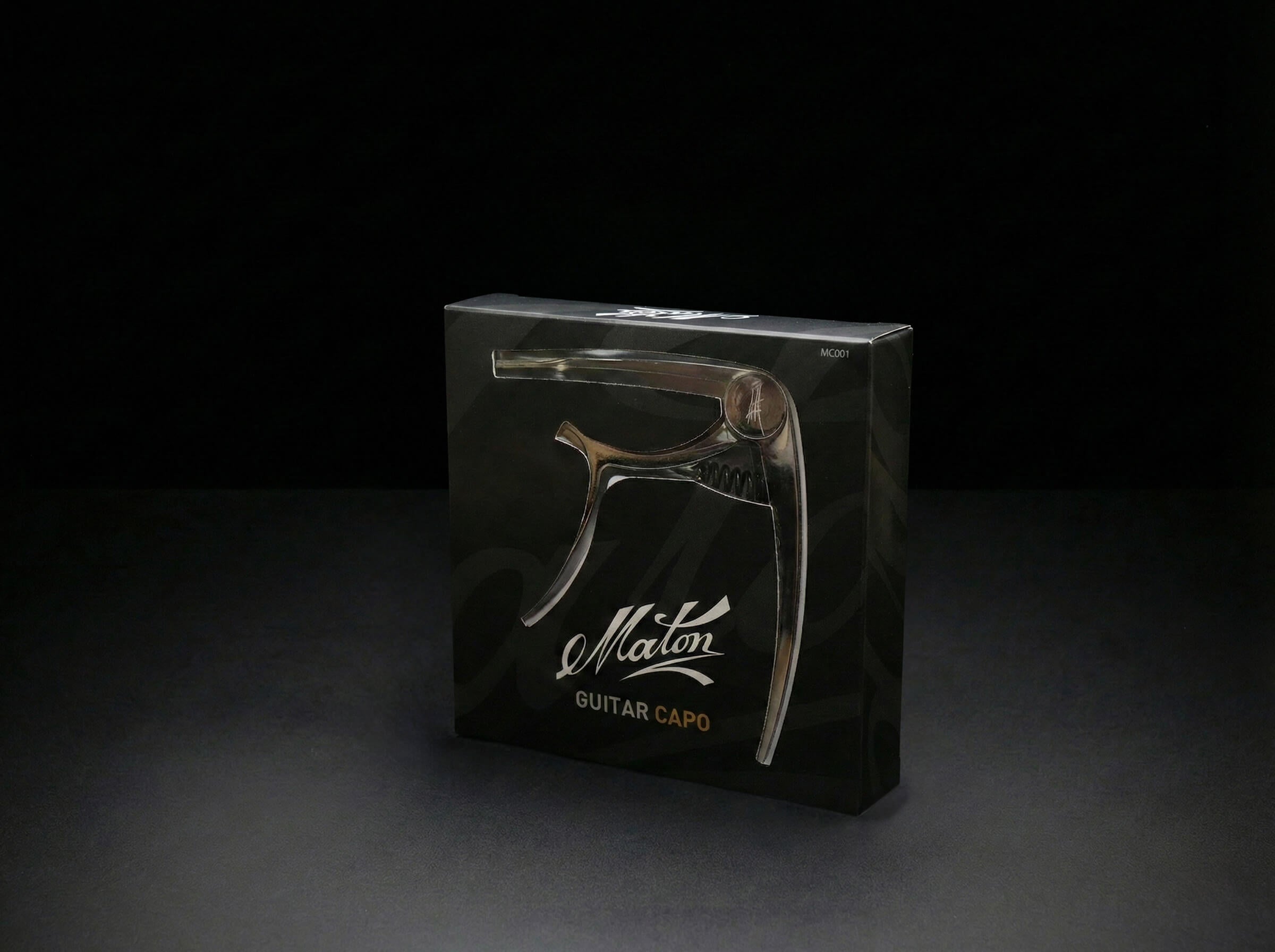 Maton guitar capo clipped on guitar neck showing the adjustable clamp and sleek black design.