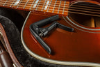 Jim Dunlop Trigger Fly Capo in gunmetal, a guitar capo with a sleek design, shown on a guitar neck.