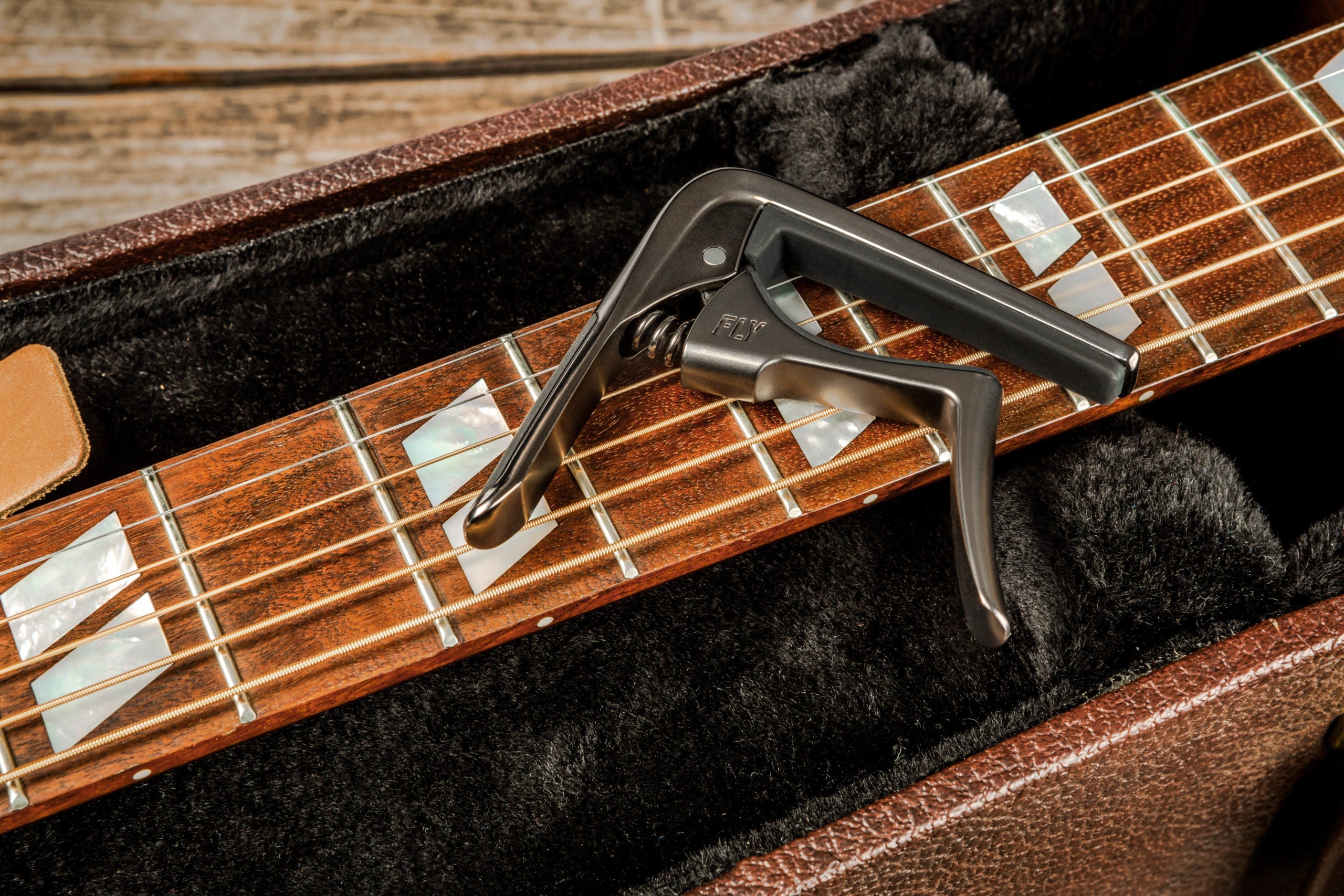 Jim Dunlop Trigger Fly Capo in gun metal attached to a guitar neck, showcasing its compact design for quick, secure string clamping.