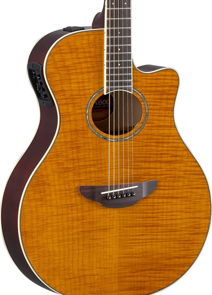 Yamaha APX600 thinline acoustic guitar with flamed maple top and pickup, showing the body and neck in an outdoor setting
