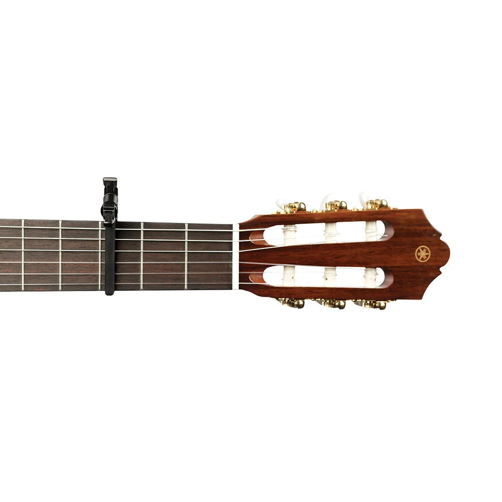 D'Addario Planet Waves PW-CP-13 Artist classical guitar capo in black resting on a wooden guitar neck.